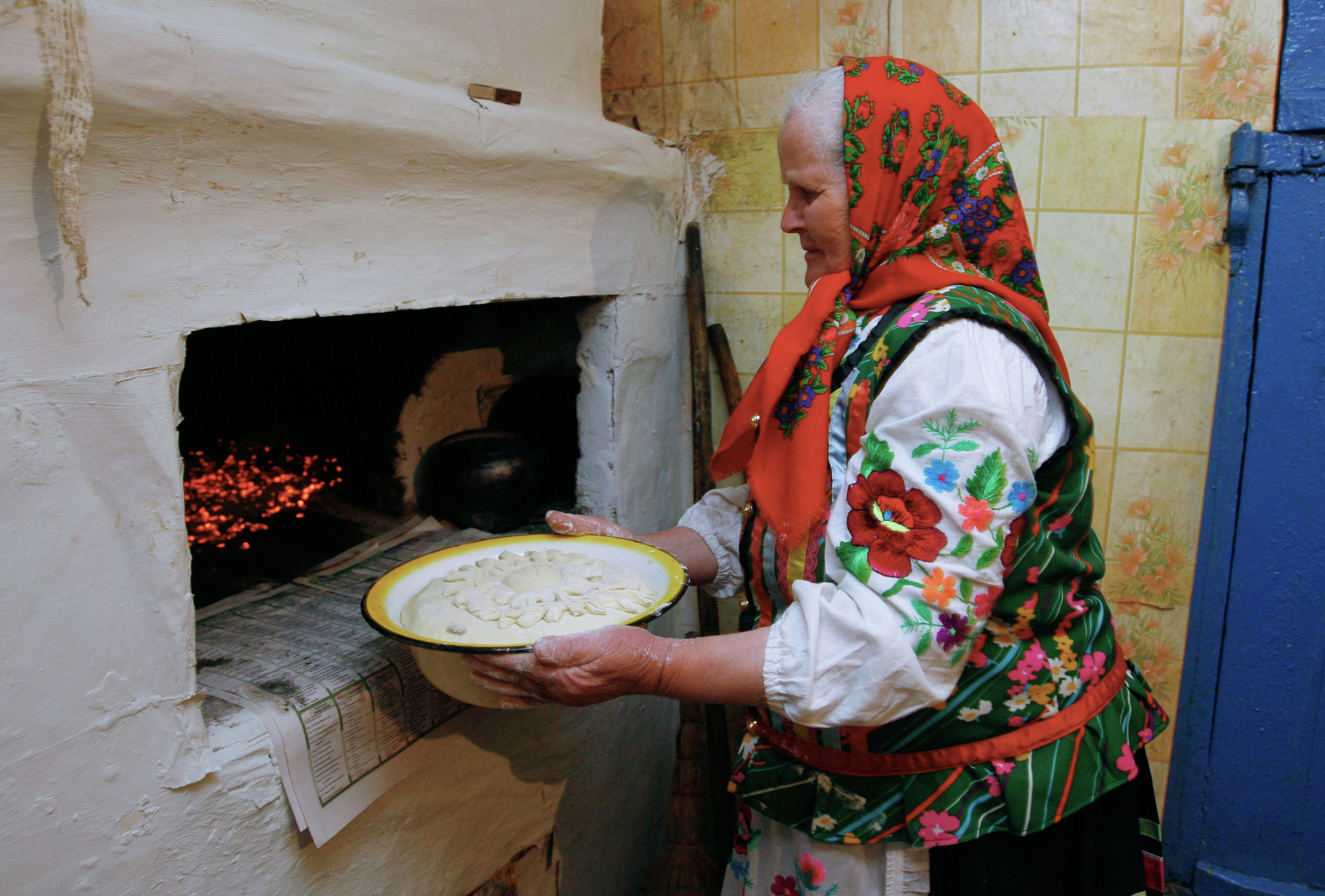 Бабушка печет хлеб в печи